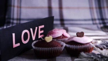 Kremayla süslenmiş ev yapımı çikolatalı kekler ve çikolatalı aşk kalpleri. 