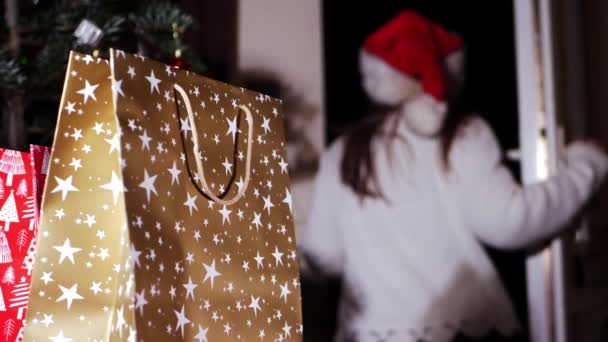 Різдвяні подарункові пакети зі святковою жінкою на задньому плані — стокове відео