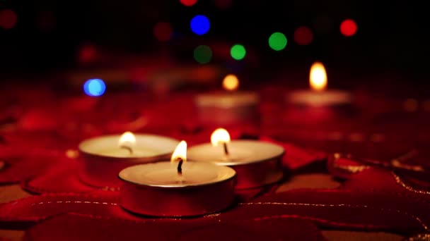 Velas Tealight sobre fondo rojo con luces navideñas — Vídeo de stock