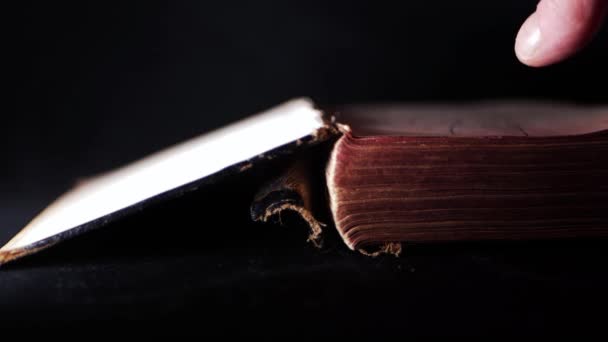 Mão abrindo um velho livro desgastado sobre fundo escuro — Vídeo de Stock