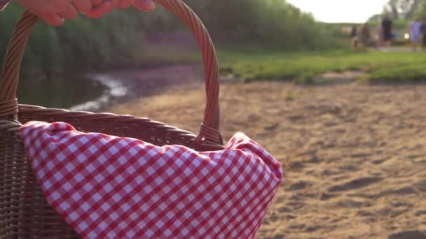 La celebración de la cesta de picnic con tela de jengibre rojo por el disparo del lago — Vídeos de Stock