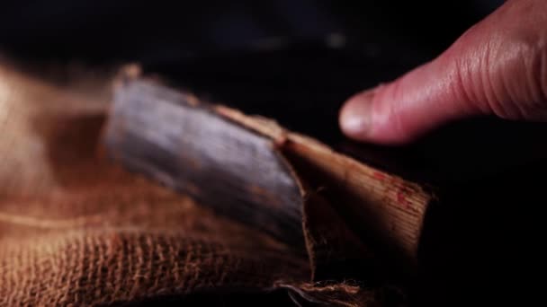 Hand opent oude versleten boek over hessian zak en donkere rook achtergrond — Stockvideo