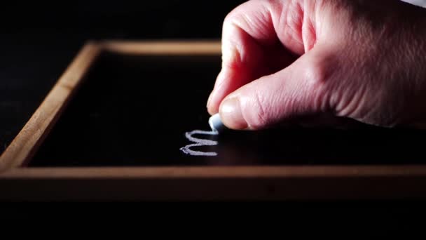 Χέρι χρησιμοποιώντας κιμωλία για να σχεδιάσετε σε έναν πίνακα — Αρχείο Βίντεο