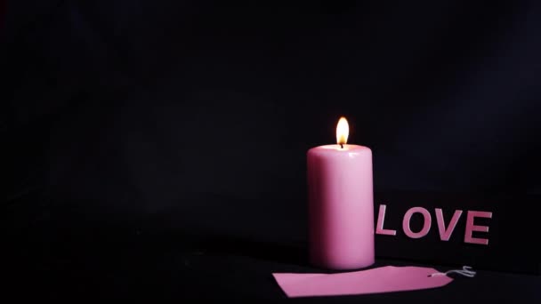 Romantic pink candle on black background wide shot — Stock Video