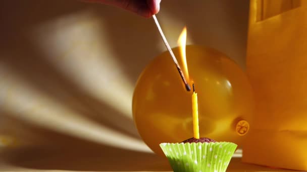 Iluminando uma única vela de aniversário amarela em um cupcake — Vídeo de Stock