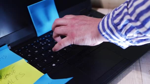 Umgeben von Notizen und Notizen tippt ein fleißiger Arbeiter auf seinem Laptop — Stockvideo