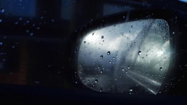 Driving through urban area in the rain at night through view of rear view mirror — Stock Video