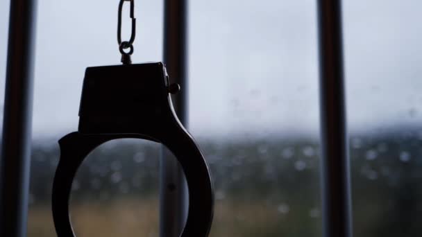 Handcuffs silhouette swing on prison bars — Stock Video