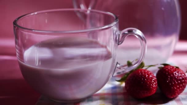 Vaso de batido de fresa sobre fondo rosa — Vídeo de stock