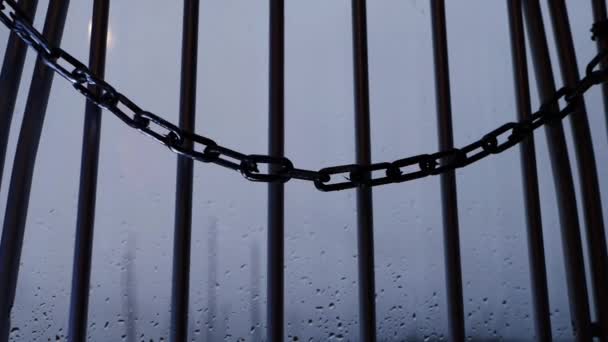 Kedjor hänger på fängelsegaller mot fönster — Stockvideo