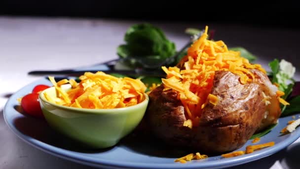 Gebakken jasje aardappel belegd met geraspte kaas — Stockvideo