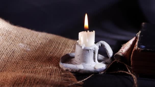 Ancient worn book and candle on hessian sack — Stock Video