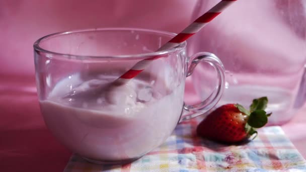 Deixar cair morangos frescos no batido de leite no fundo rosa — Vídeo de Stock