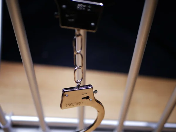 Kelepçeler hapishane parmaklıklarında sallanıyor.