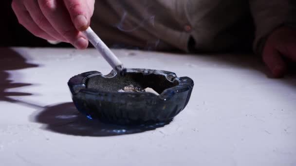 喫煙者はタバコ灰を汚れた灰皿にぶつける — ストック動画