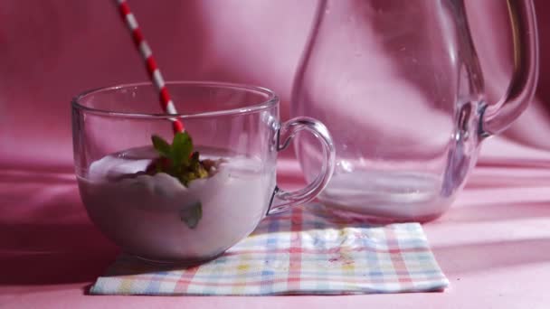 Dropping fresh strawberries into milkshake on pink background — Stock Video
