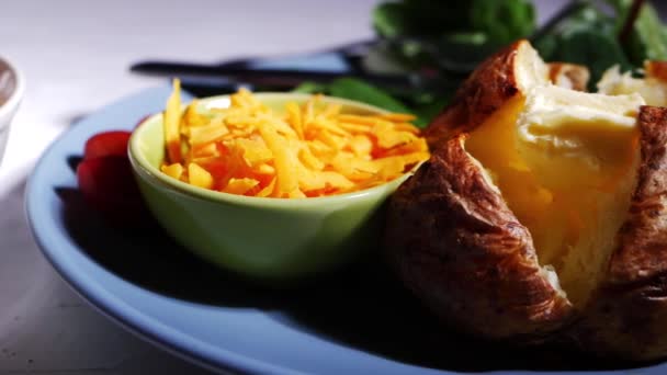 Baked jacket potato with cheese and salad sides — Stock Video
