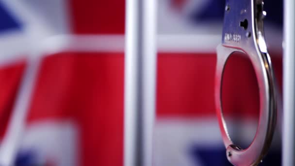 Manette altalena sulle sbarre della prigione con Union Jack bandiera britannica sfondo — Video Stock