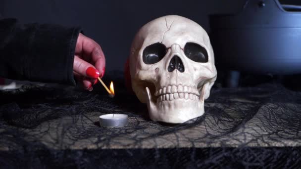 Manos de bruja malvada con vela de iluminación de cráneo — Vídeos de Stock