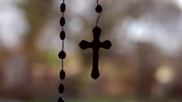 Rosenkranz Perlen Kruzifix hängt auf Bokeh Hintergrund — Stockvideo