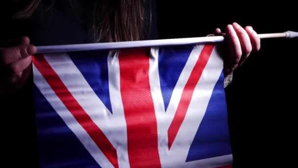 Mano ondeando bandera británica Union Jack sobre fondo oscuro — Vídeos de Stock