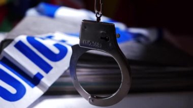 Polis dosyalarıyla birlikte kelepçeler sallanıyor.