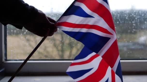 Hand zwaaiende Britse Union Jack vlag op regenachtige dag — Stockvideo