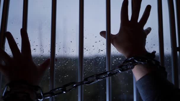 Рука заключенного в цепях против тюремных решёток — стоковое видео