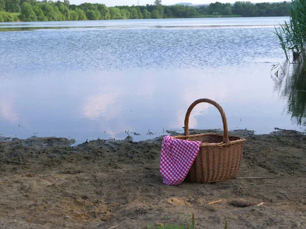 湖のピクニックバスケットと赤い銀杏の布 — ストック写真