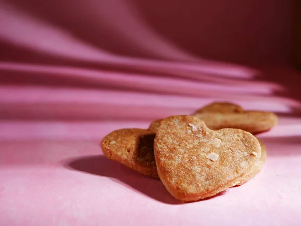 Corazón en forma de galletas frescas horneadas plano medio sobre fondo rosa —  Fotos de Stock
