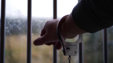 Elleri kelepçeli mahkum parmaklıklardan uzanıyor.