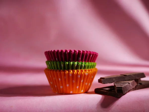 Maletas de bollo en diferentes colores con chocolate para hornear sobre fondo rosa — Foto de Stock