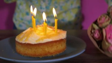 Kadın pembe gülleri doğum günü pastasının yanına yerleştirir 