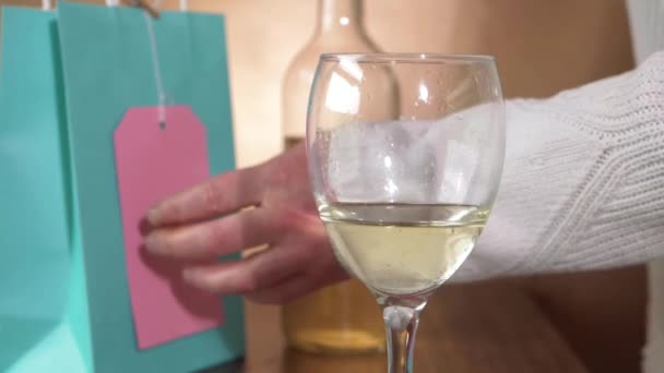 Szklanka białego wina z kobietą otwierający prezent w tle — Wideo stockowe