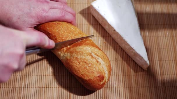 Tangan mengiris roti baguette dengan keju Prancis brie — Stok Video