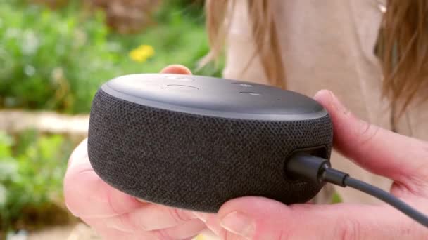 Woman holds smart home assistant voice activated in the garden — Wideo stockowe