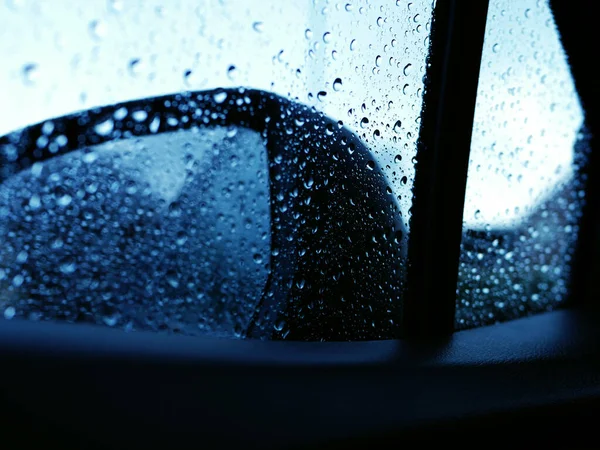 Driving in the rain through view of rear view mirror medium shot — Zdjęcie stockowe