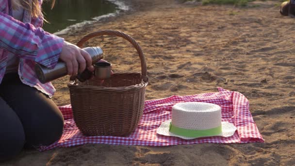 Mujer con cesta de picnic y termo en la arena de la playa — Vídeo de stock