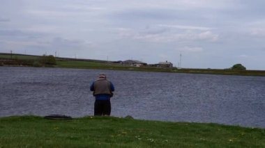 Kırsal kesimde gölün kenarında dinlenen balıkçı.