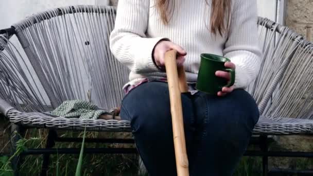 Woman holding a wooden walking stick stands up — Vídeos de Stock