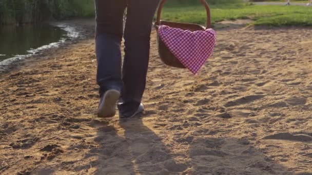 女性はヴィンテージピクニックバスケットと湖の海岸に沿って歩く — ストック動画