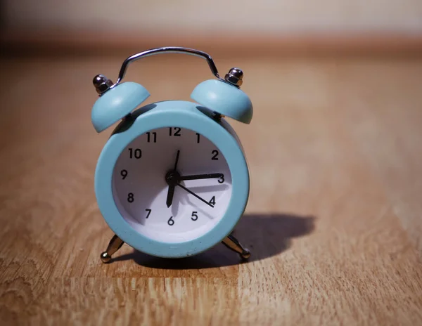 Traditional alarm clock on wooden background at six in the morning — Stockfoto