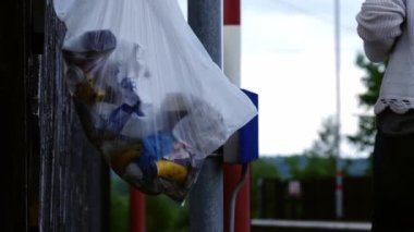 Banliyö çalışanı çöpü demiryolu platformuna koyar. Orta boy, yavaş çekim, seçici odak noktasına yakınlaştırır.