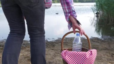 Kadın klasik piknik sepetiyle gölün kıyısında duruyor. Yavaş çekim, seçici odak noktası. 