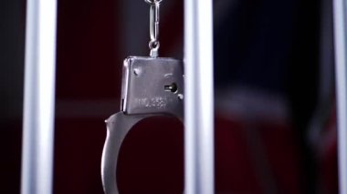 Kelepçeler hapishane parmaklıklarında sallanır. Yakın çekim yavaş çekim seçici odaklanma.