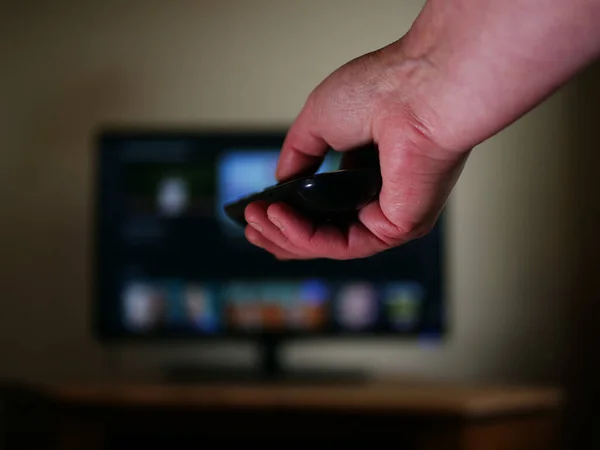 Hand using television remote to change channel medium shot selective focus
