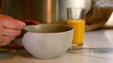 Taze portakal suyuyla granola kahvaltısı yaparken yavaş çekimde odaklan.
