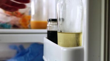 Buzdolabından şarap şişesine uzanan el zoom çekimine odaklanır.