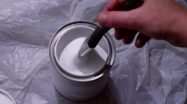 Boya fırçasını beyaz parlak boya tenekesine daldırıyorum yavaş çekim çekimini kapat seçici odağı yakınlaştır 