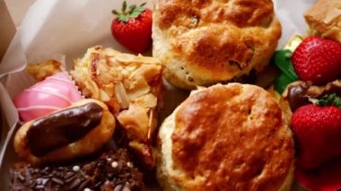 Cream tea with selection of cakes scones and sweets with strawberries close up overhead zoom shot selective focus